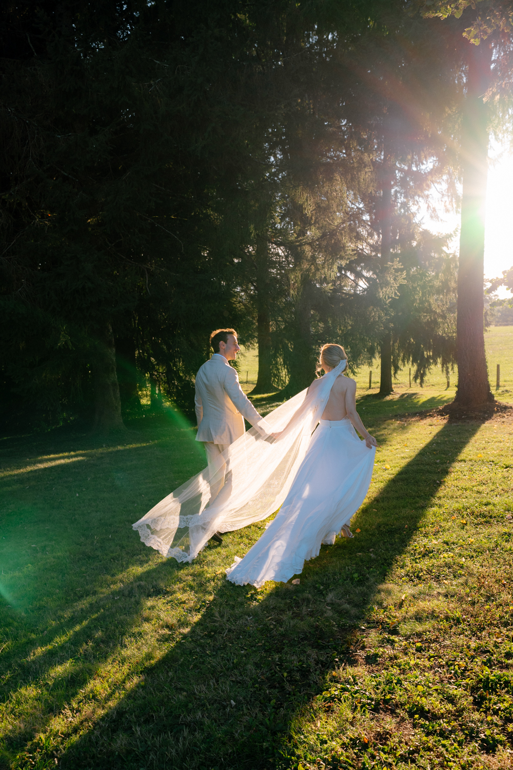 Mariés qui marchent sous le soleil couchant pendant leur séance couple à leur mariage