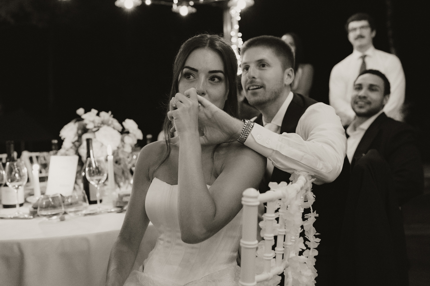 Mariée embrasse la main de son mari pendant le dîner de leur mariage